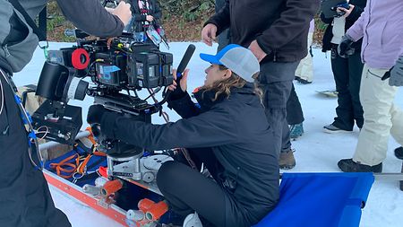 DP Eve Cohen with camera on sled at ski resort set